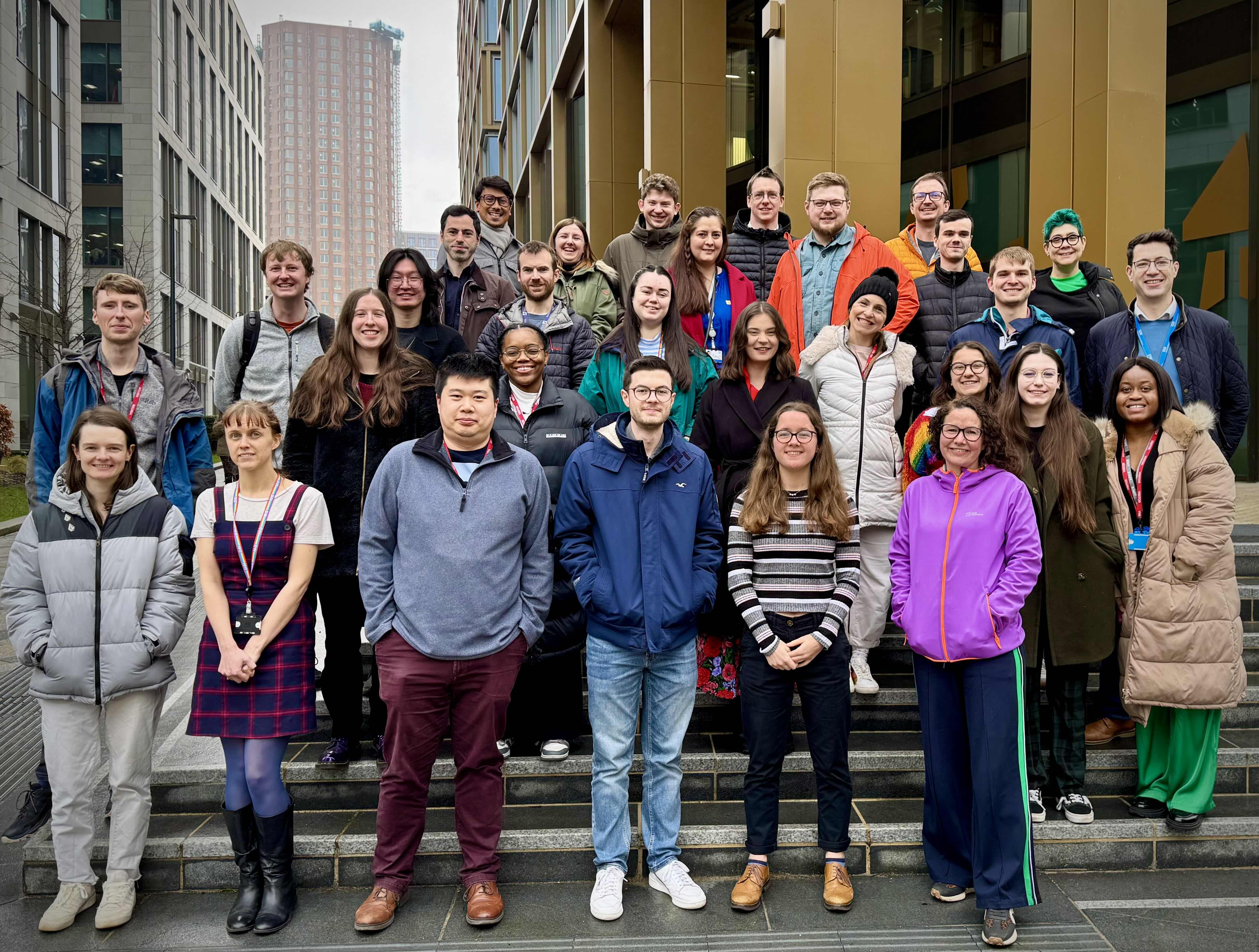 Data science team photo, all stood on some stairs outdoors.